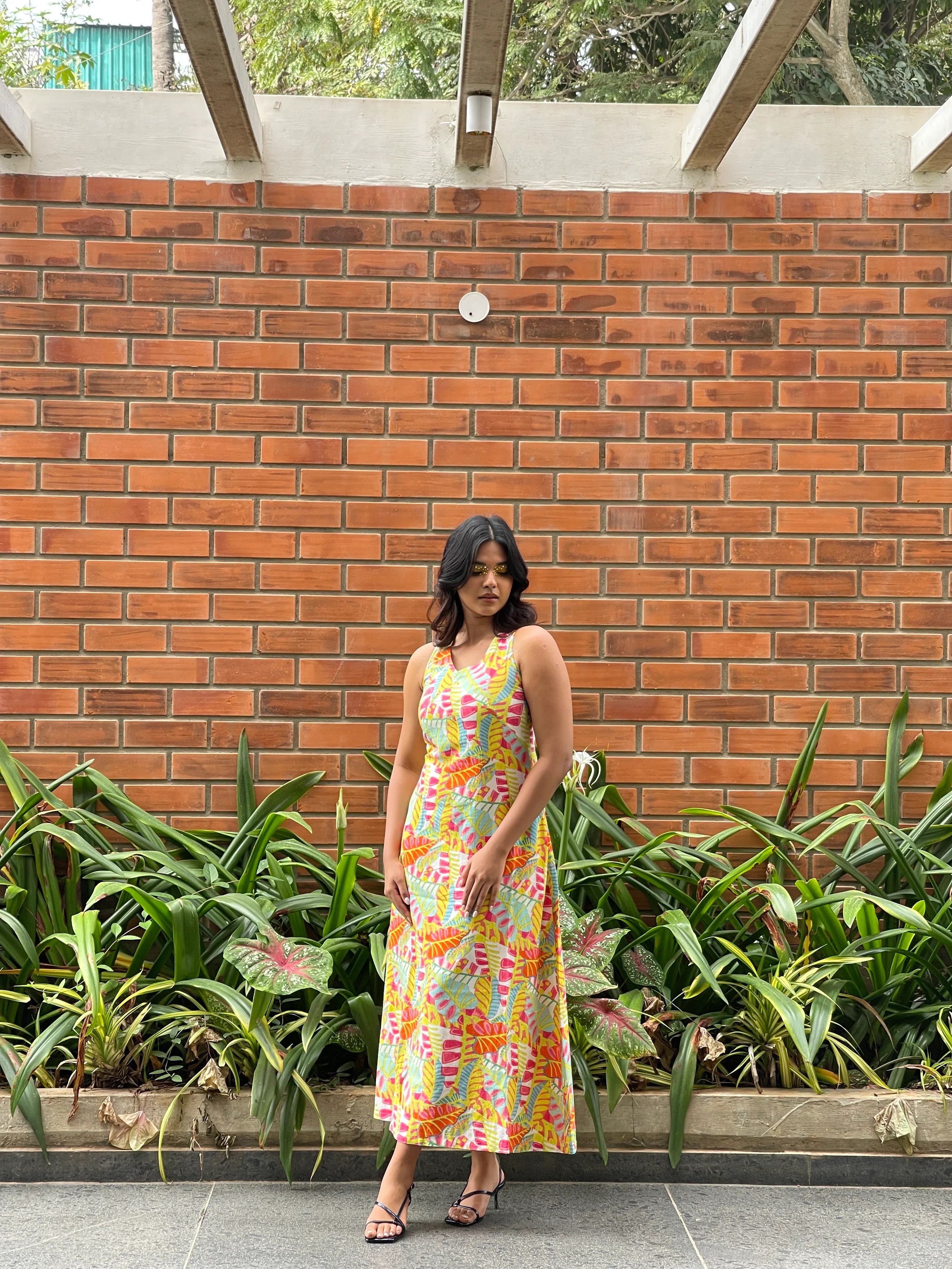 Woman in a colorful dress standing on a brick patio with plants around