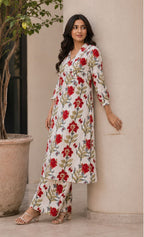 Shinyora red floral print cotton kurta set with V-neckline and matching pants worn by a woman leaning on a pillar