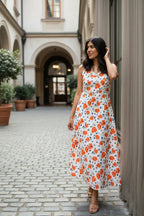 Woman in a floral dress standing in an outdoor setting with architectural elements.